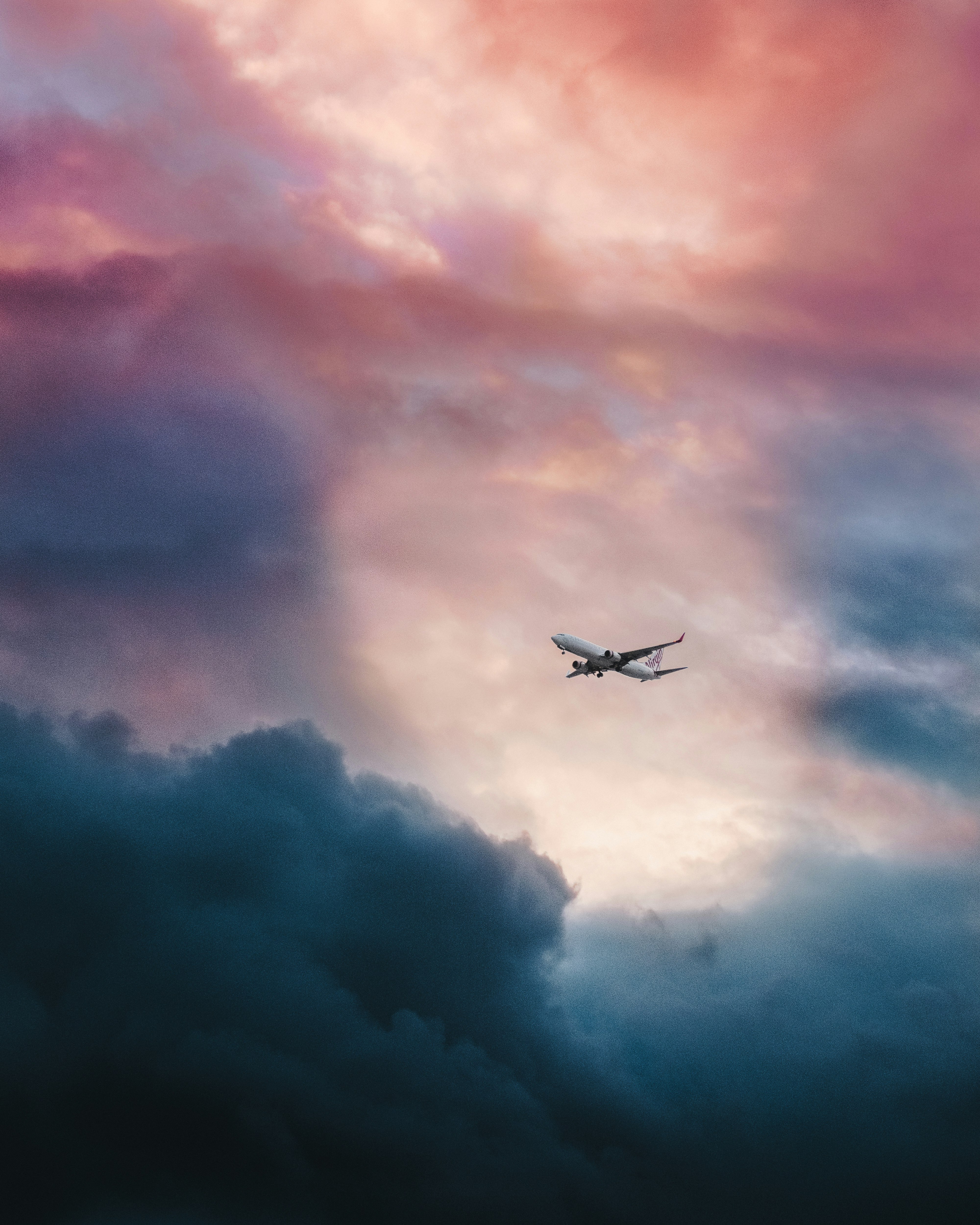 white plane flying over gray clouds